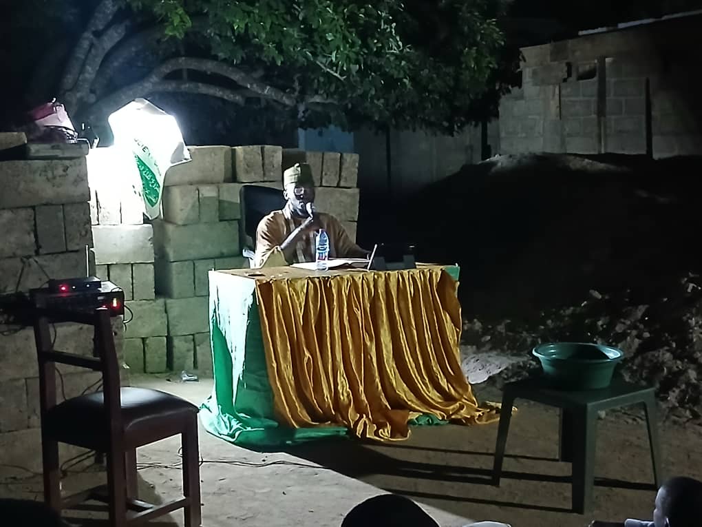Sheikh Ishaque Abdallah holding a microphone at a night dawa event