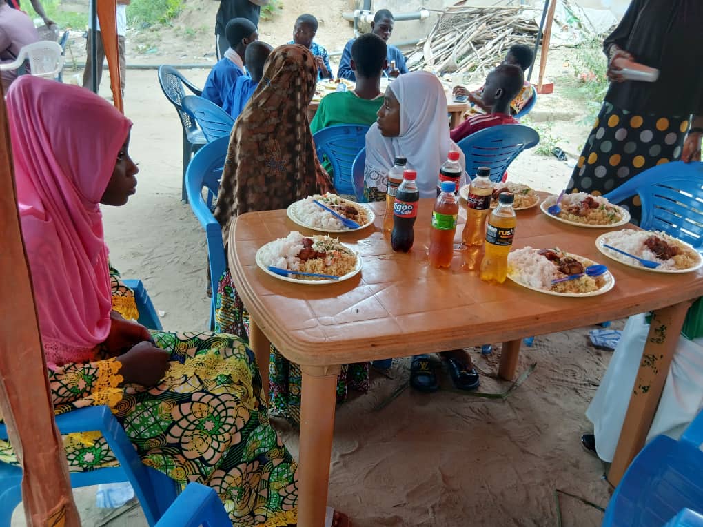 Islamic youth gathered around a table with food at a community party